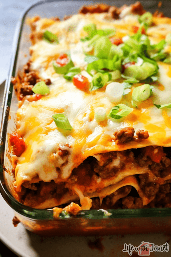 Taco lasagna slice on a plate with guacamole and sour cream on the side