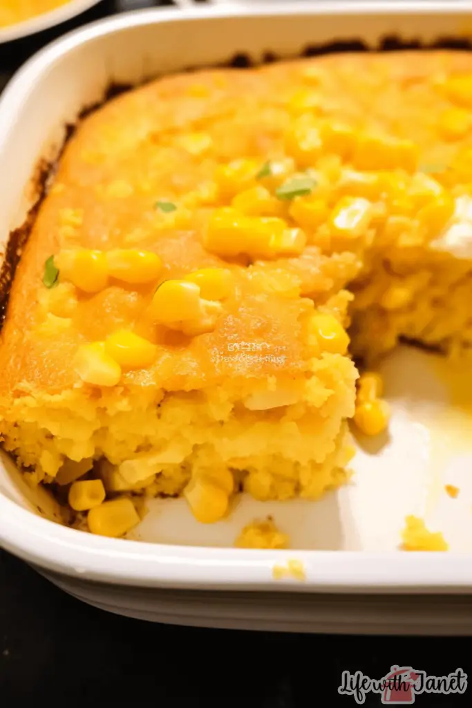 A close-up view of a scoop of Creamy Corn Casserole, revealing its rich texture, colorful bell peppers, and hints of shredded chicken, all sitting on a rustic wooden table.