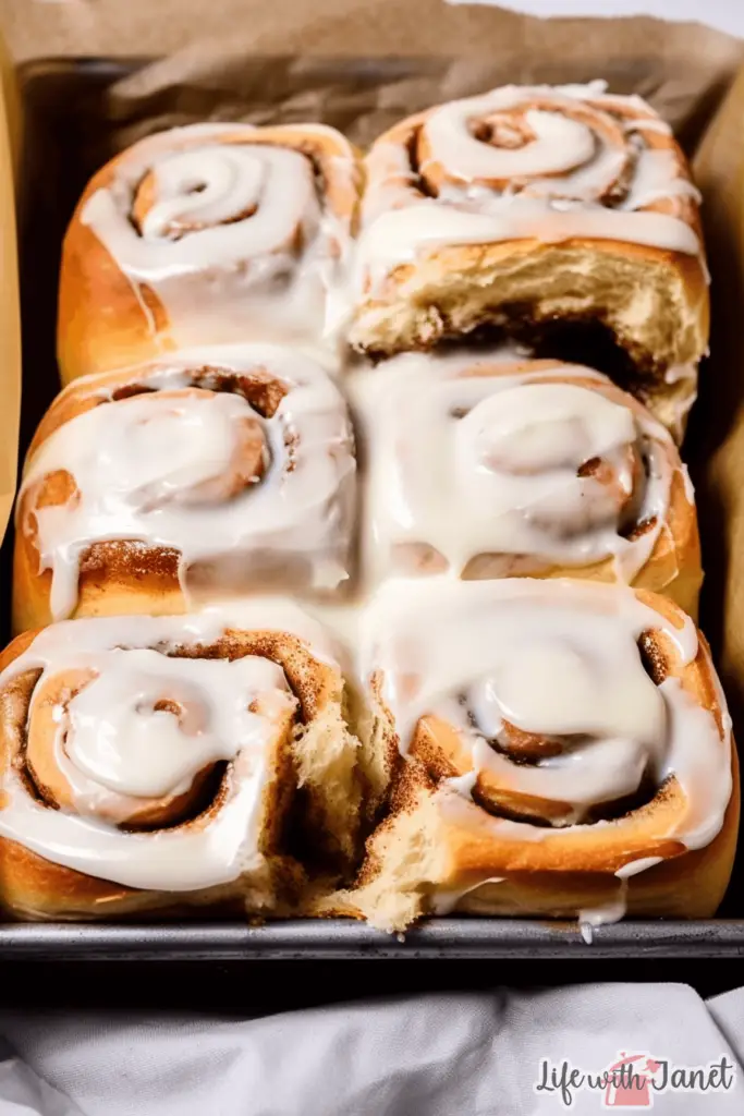 Freshly baked overnight cinnamon rolls topped with creamy icing on a white plate.