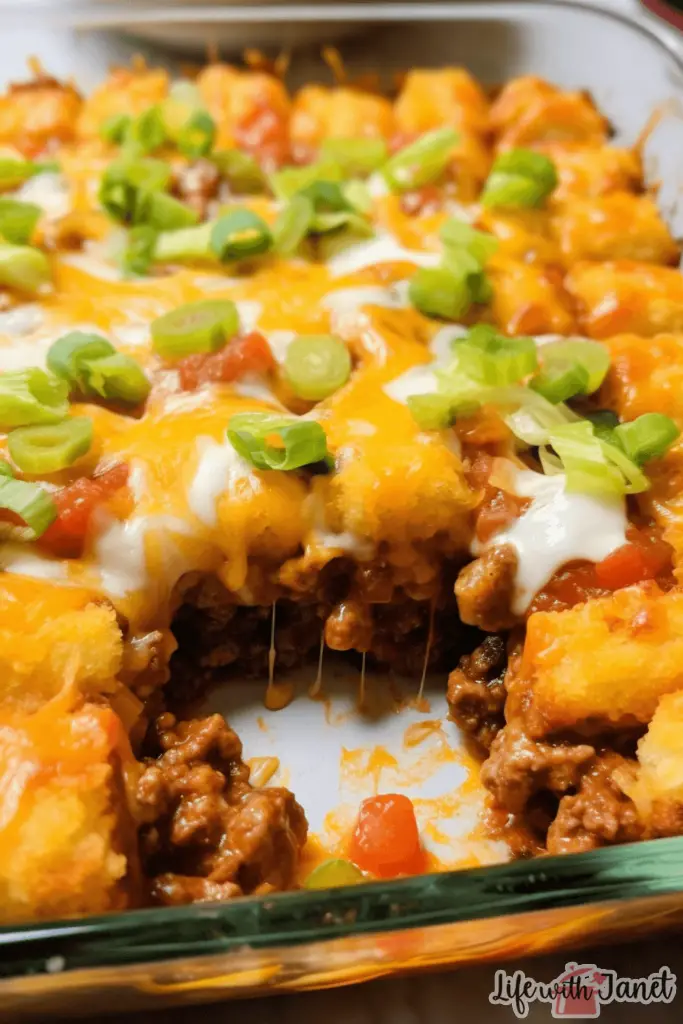 A family-sized serving of taco tater tot casserole on a wooden table, accompanied by side dishes of guacamole and salsa.